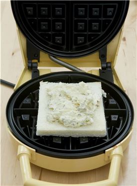 5. 와플기계에 식빵을 올린 후 견과류를 넣은 크림치즈를 올린다.