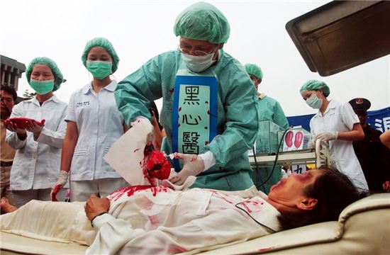 체포된 파룬궁 수련자들의 생체 장기적출을 시연하고 있는 파룬궁수련자들. 사진 = 연합뉴스/AP