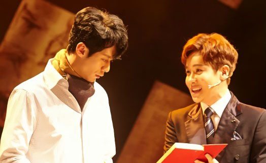 ▲ 뮤지컬 ‘더 픽션’(연출 윤상원) 공연장면 중 그레이가(왼쪽, 주민진 분)가 와이트(강찬 분)가 보여주는 소설을 보고 있다. © 사진=HJ컬쳐