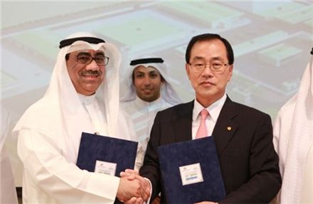 한화건설 김현중 사장(우측)과 발주처인 쿠웨이트 KOTC의 나빌 모하메드 보리슬리 회장(Nabil M. Bourisl, 좌측)이 계약서에 서명을 마치고 악수를 나누고 있다. 
