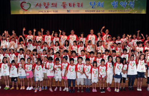 최경환 장관, 김쌍수 한전 사장, 주강수 가스공사 사장, 이태용 에관공 이사장 등 지경부와 산하기관장들이 전국에서 모인 아동들과 협약식 기념촬영을 하고 있다
