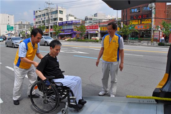 이용선 서울시설공단이사장이 장애인 콜택시를 이용하는 시민의 휠체어를 밀고 있다.