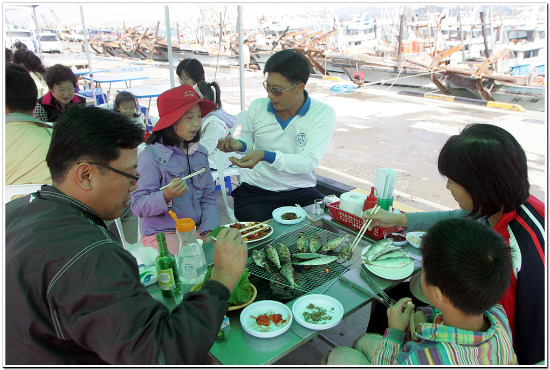 서천 바닷가에서 제철인 전어를 구워먹는 관광객들.