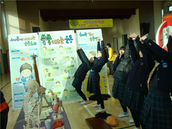 운동부스에서는 학생들이 척추와 키크는데 도움이 되는 운동 자세를 취하고 있다.

