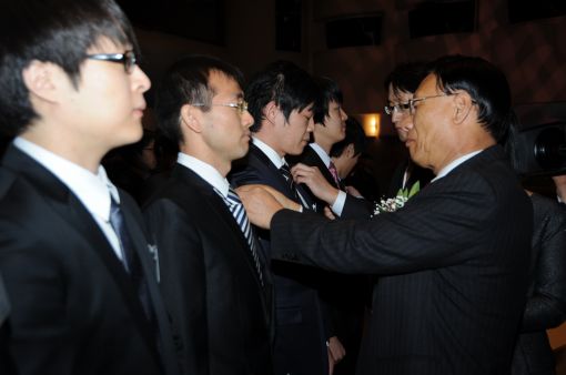김종신 사장이 입사식에서 신입 직원들에게 회사 배지를 달아주고 있다
