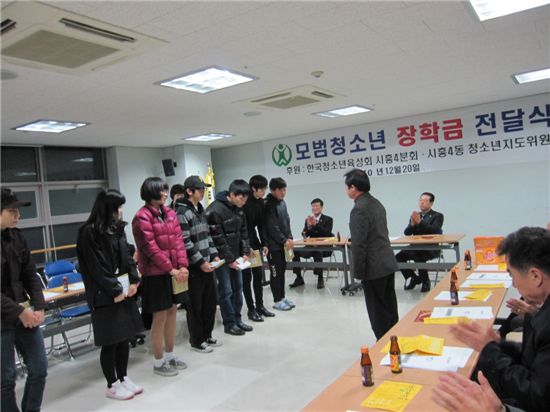 시흥4동청소년지도위원들이 모범청소년들에게 장학금을 주며 격려하고 있다.