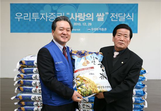 우리투자증권 이득희 감사위원(左)이 12월 29일 장안종합사회복지관에서 지역주민 대표와 함께 ‘사랑의 쌀’ 전달식을 갖고 있다.