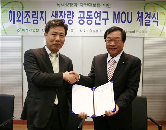 조현제 녹색사업단장(왼쪽)과 고명호 한솔홈데코 대표이사가 협약서를 펼쳐보이며 악수하고 있다.