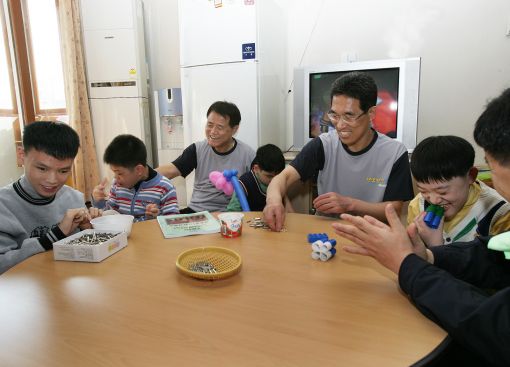 김쌍수 한국전력 사장(사진좌측)과 김주영 노조위원장(사진우측)이 시각장애 어린이들과 함께 재활교육 프로그램인 콘센트를 조립하고 있다.