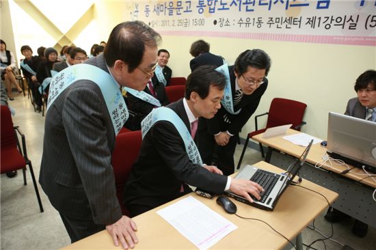박겸수 강북구청장(가운데)가 동새마을문고 U-도서관 구축 시연회에 참석해 시연해보고 있다.