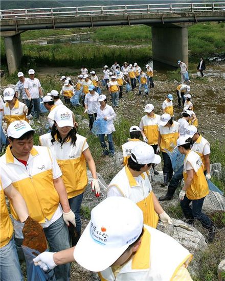 웅진코웨이 직원들이 충청남도 공주시에 위치한 '유구천' 주변의 환경오염을 막고 깨끗한 하천을 만들기 위해 폐비닐과 쓰레기 등을 수거하고 있다. 
