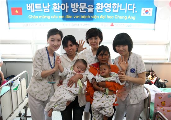 중앙대학교 병원 간호사들과 베트남 구개열 어린이 환자와 어머니들이 성공적인 수술을 기원하는 기념촬영을 하고 있다.