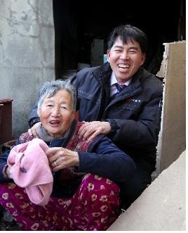 대상을 수상한 권병우 집배원이 홀로사는 어르신을 봉사하고 웃고 있다.