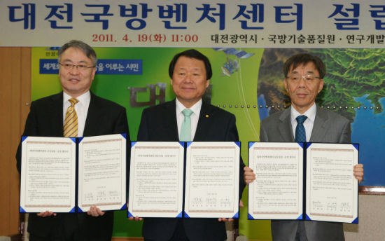 염홍철 대전시장(가운데)과 이재구 특구본부 이사장(오른쪽),  정재원 기술품질원 원장이 대전국방벤처센터 설립협약서를 펼쳐보이고 있다