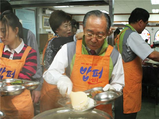 동아제약 강신호 회장이 밥퍼나눔운동본부에서 노숙자들을 위해 식판에 밥을 푸고 있다.