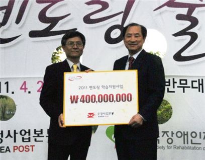 김명룡 우정사업본부장(왼쪽)이 이상철 한국장애인재활협회장에게 지원금을 전달하고 있다.