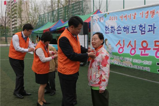 한화손해보험 봉사단이 어버이날을 맞이해 어르신들에게 카네이션을 달아드리고 있다.
