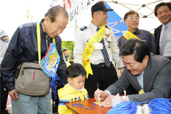 김기동 광진구청장(오른쪽)이 5일 할아버지와 어린이대공원을 찾은 어린이에게 이름을 적은 명찰을 만들어 주고 있다.