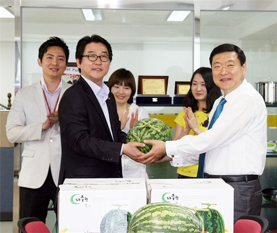  롯데홈쇼핑 식품주방팀 최성진 팀장(왼쪽)이 협력업체 엘샴마 김민호 대표(오른쪽)에게 수박을 전달하고 있다.
