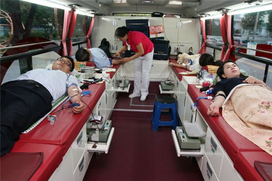 26일 LS타워 주차장에 자리잡은 헌혈버스에서 LS전선·산전·엠트론 3社 임직원이 헌혈에 참여하고 있다.