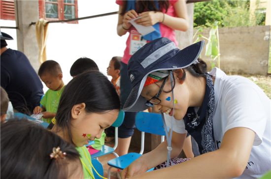 LS그룹이 파견한 해외봉사단 대학생들이 현지 어린이들과 스티커 놀이를 하고 있다.