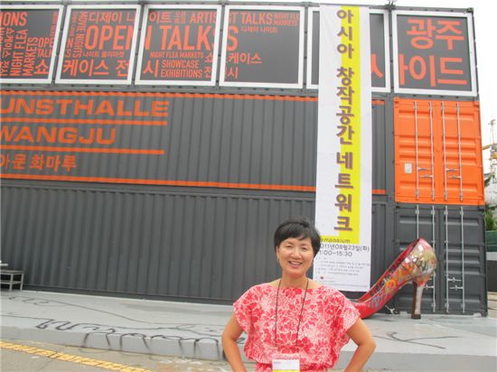 남정숙 '아시아 창작공간 네트워크' 총감독이 행사장 앞에서 환히 웃고 있다. 