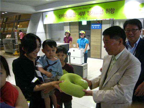 김재건 진에어 대표(오른쪽)가 탑승객에게 취항 기념 선물(목쿠션)을 증정하고 있다.