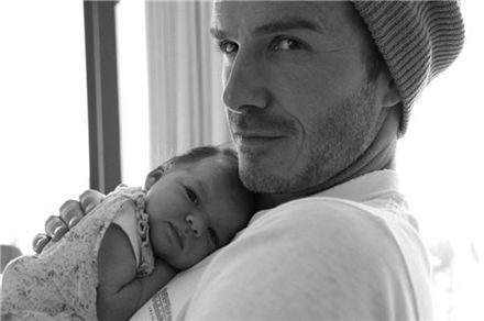 축구스타 데이비드 베컴이 갓난 아기 하퍼 세븐을 안고 카메라 앞에 서 있다.
