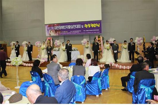 ‘제13회 대전시장애인자활실천대회 및 합동결혼식’ 때 신랑 신부들이 단상에 줄지어 서 있다.