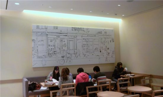 카페 아티제 매장 내부, 한 벽면 전체르 일러스트벽화가 차지하고 있다.