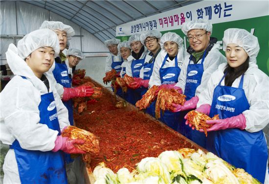 삼성엔지니어링 임직원들과 안성 미리내 마을 주민들이 함께한 '사랑의 김장 담그기'행사에서 담근 김치를 내밀며 활짝 웃고 있다.