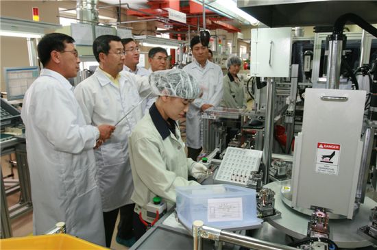 구자홍 LS그룹 회장이 전기자동차 핵심부품 생산현장을 방문해 설명을 듣고 있다.