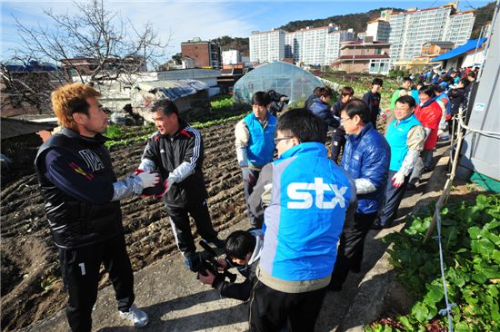 김병지 선수(왼쪽)를 비롯한 프로축구 경남FC 선수들과 서포터즈, STX그룹 임직원들이 5일 창원시 진해구 경화동에서 어려운 이웃들에게 전달할 연탄을 나르고 있다. 
