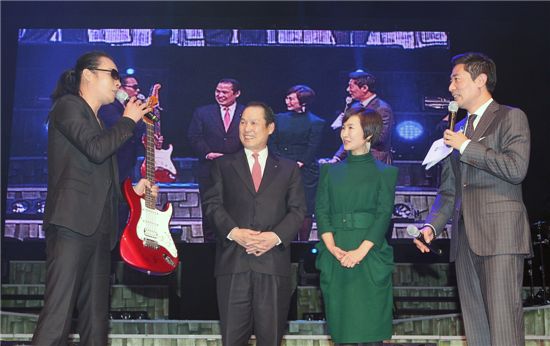 우리투자증권은 12월 7일 용산소재 블루스퀘어 콘서트홀에서 '따뜻한 겨울이야기'를 주제로 'VIP 초청 송년 콘서트」를 개최했다. 이날 '부활' 애장품 경매 이벤트에서 가수 김태원씨가 우리투자증권 황성호 사장과 월드비전 친선대사인 배우 정애리씨에게 본인이 직접 사용하던 기타를 경매에 붙이면서 기타의 내력에 대해 설명하고 있다. (왼쪽부터 가수 김태원, 우리투자증권 황성호 사장, 배우 정애리씨, 사회자 김범수씨) 