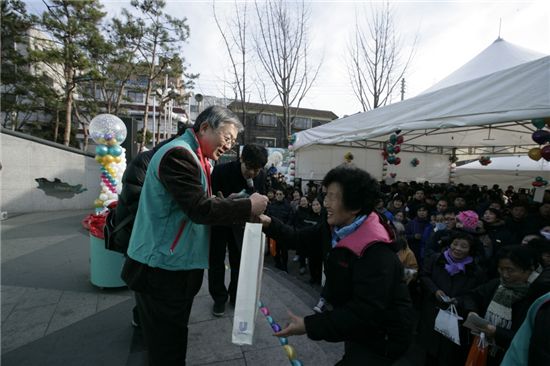 ▲안산 원곡동에서 열린 사랑의 바자회에 참여한 고객에게 선물을 증정하고 있는 김종열 하나금융 사장(왼쪽)
