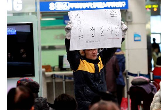 대전역 맞이방에서 '경축 김정일 사망' 문구가 적힌 종이를 펼쳐보이고 있는 한 시민.(디트뉴스24)