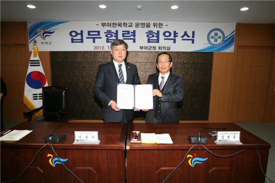 이용우(왼쪽) 부여군수와 김헌중 한국목구조기술인협회장이 한옥학교 설립운영관련 협약서를 펼쳐보이고 있다. 