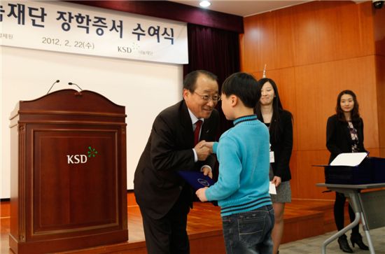 "씩씩하게 자라다오" 김경동 예탁결제원 사장이 초등학생에게 장학증서를 수여하고있다. 