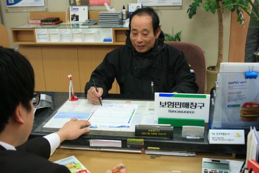 NH농협은행 방카슈랑스 1호 가입자인 독도이장 김성도 씨가 보험 서류에 서명을 하고 있다.