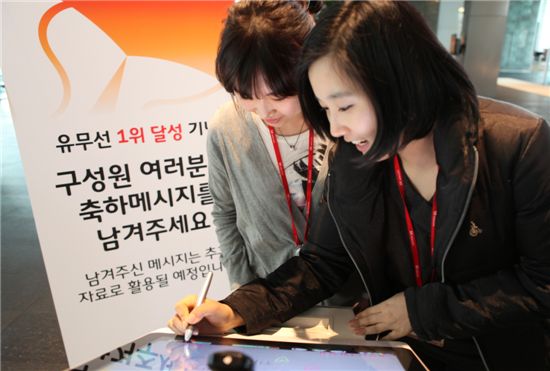SK텔레콤 직원들이 본사 로비에 설치된 전자보드에 유무선 1위 달성 축하메시지를 작성하고 있는 모습.
