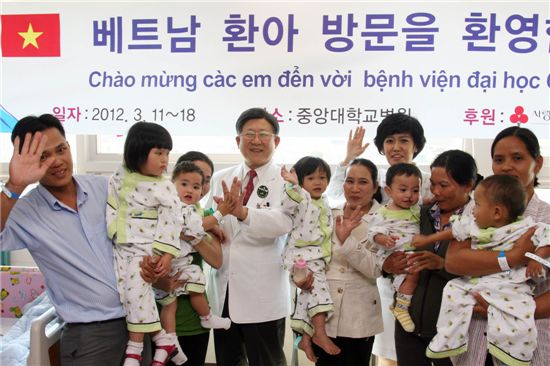 ▲김성덕 중앙대의료원장(가운데 흰 웃옷)이 베트남에서 온 어린이 환자들 및 보호자와 기념촬영을 하고 있다.
