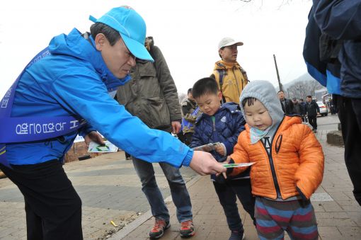 신충식 농협금융지주 회장이 17일 청계산에서 아버지와 함께 온 꼬마 등산객에게 꽃씨를 나눠주고 있다.