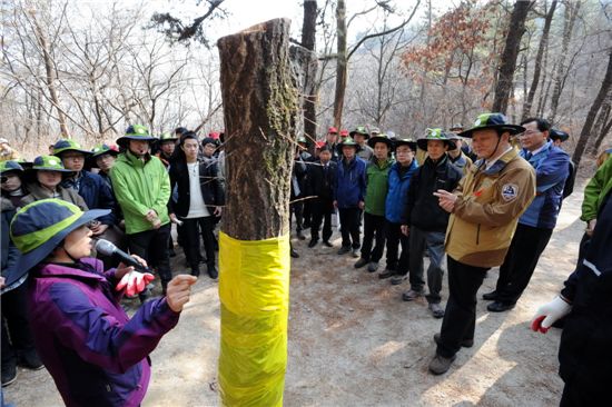 정광수 국립공원관리공단 이사장, 이돈구 산림청장, 박겸수 서울 강북구청장과 대학생들이 참나무시들음병방제에 대해 설명을 듣고 있다.