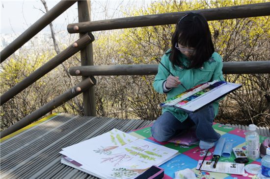 한 어린이가 응봉산 개나리축제에서 그림을 그리고 있다.