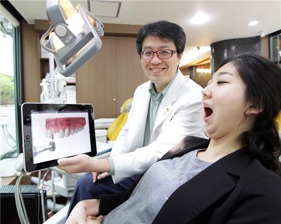 SK텔레콤의 태블릿 PC기반 치과전용 의료 솔루션인 ‘스마트 덴탈’을 도입한 한 치과 병원에서 담당의사가 환자에게 태블릿 PC를 이용해 치료과정을 설명하고 있는 모습.