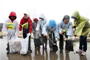 지난 21일 봄비가 내리는 가운데 박준 대표이사(왼쪽에서 두번째)를 비롯한 농심 임직원들이 벚꽃시즌을 맞은 여의도 한강시민공원에서 청소봉사활동을 하고 있다. 