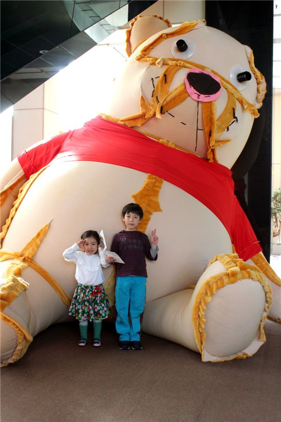 어린이 관람객이 정문경 작가의 대형 곰인형 앞에서 포즈를 취하고 있다.