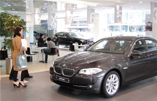 BMW 전시장에서 고객들이 차량을 둘러보고 있다.