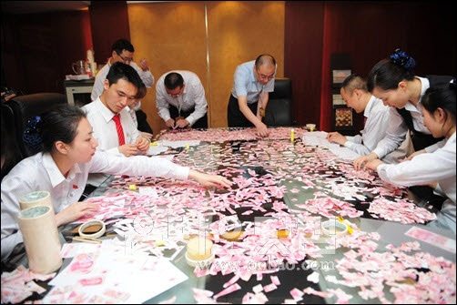 ▲ 지난 3일 중국은행 쓰촨분행 직원들이 수천조각으로 찢긴 지폐 조각을 맞추고 있다.(출처: 온바오닷컴)