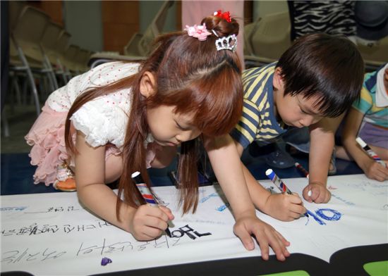 '금천에코라이프데이'에 참석한 아이들이 대형 플랫카드에 에너지 절약을 실천하는 서명을 하고 있다